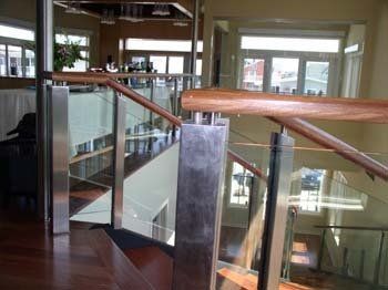 A staircase with a glass railing and wooden handrails
