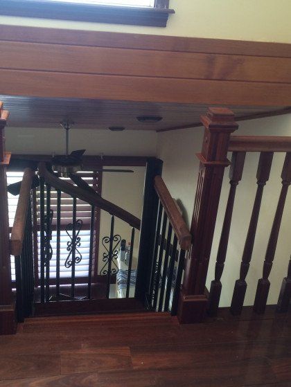 A wooden staircase with a black railing and a ceiling fan
