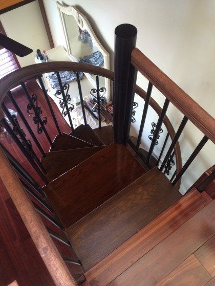 A spiral staircase with a black railing and wooden steps