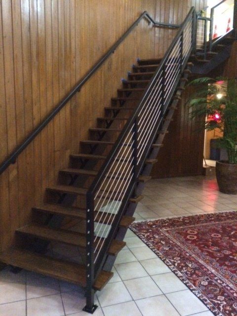 A wooden staircase with a metal railing in a room