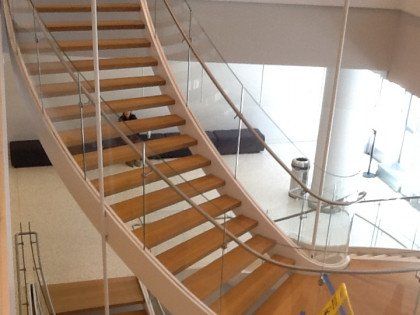 A curved staircase with wooden steps and a glass railing