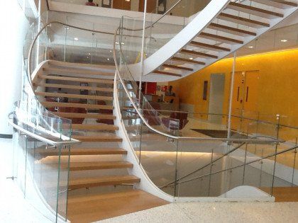 A curved staircase with a glass railing in a building