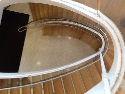 A spiral staircase with a white railing and wooden steps