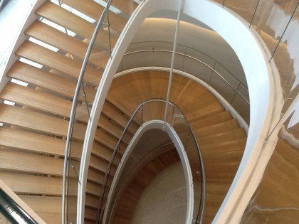 A spiral staircase with wooden steps and a glass railing