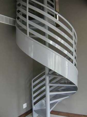 A spiral staircase with a white railing in a room.