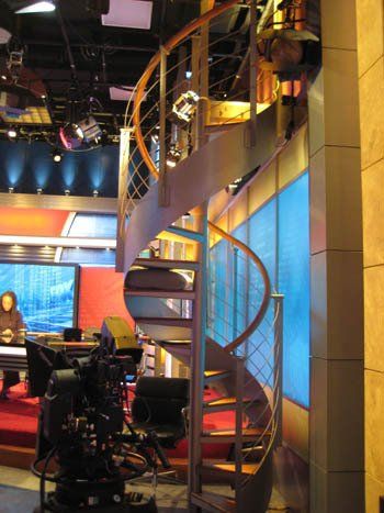 A spiral staircase leading up to the second floor of a news studio