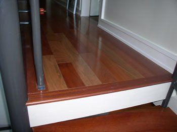 A wooden staircase with a white railing and a wooden floor.