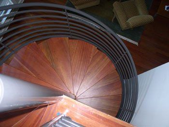 A wooden spiral staircase with a metal railing in a living room