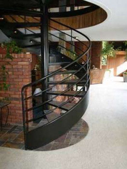 A spiral staircase in a house with a black railing