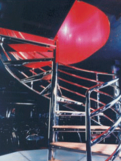 A red spiral staircase with a black railing