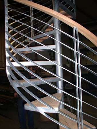 A spiral staircase with a metal railing and wooden steps.