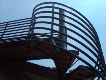A spiral staircase with a metal railing and a blue sky in the background