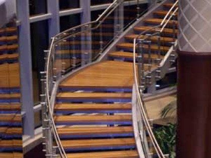 A set of wooden stairs with a glass railing in a building.