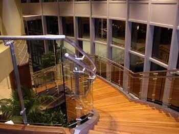 A staircase with a glass railing in a building with lots of windows.