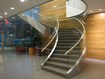 A curved staircase with a glass railing in a building