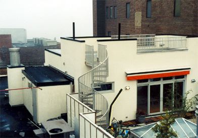 A white building with a spiral staircase on the roof