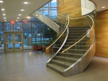 A spiral staircase with a glass railing in a lobby