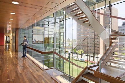 A man is standing on a balcony next to a staircase in a building.