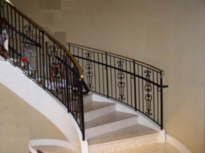 A curved staircase with a wrought iron railing