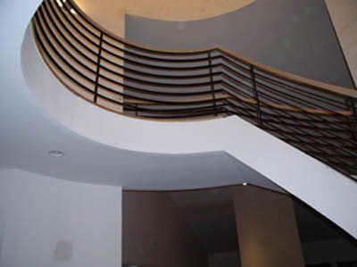 A curved staircase with a metal railing and a wooden handrail