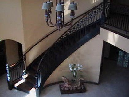 An aerial view of a curved staircase with a chandelier above it