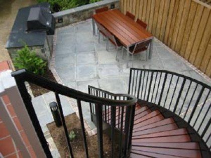 A spiral staircase leading up to a patio with a table and chairs.