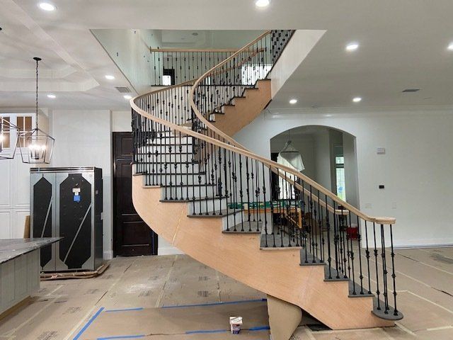 A wooden spiral staircase with a wrought iron railing