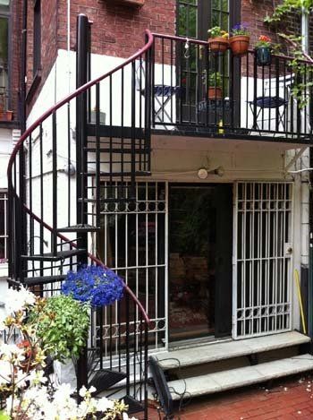 A spiral staircase leading up to a balcony on the side of a building.