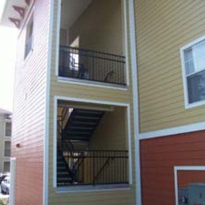 A building with stairs leading up to the second floor and a balcony.