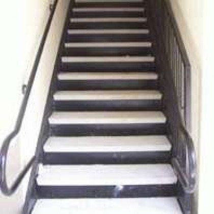 A set of stairs with white steps and a metal railing.