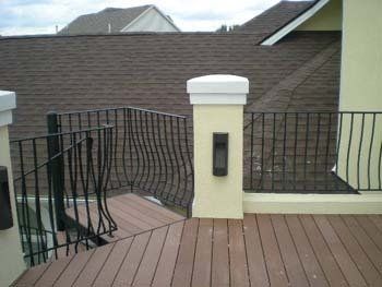 A wooden deck with a wrought iron railing and stairs leading up to it.