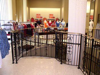 A store with a wrought iron railing and mannequins on display