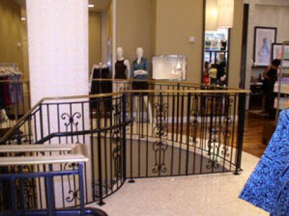 A staircase in a store with a wrought iron railing
