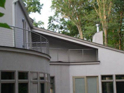 A white house with a balcony and trees in the background.