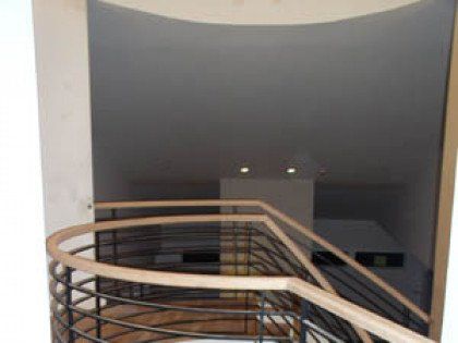 A spiral staircase with a wooden railing and a metal railing