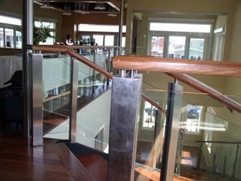 A staircase with a glass railing and a wooden handrail