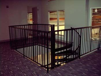 An empty room with a spiral staircase and a metal railing