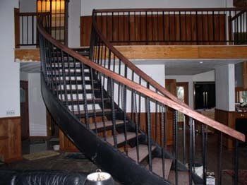A spiral staircase in a living room with a wooden railing.