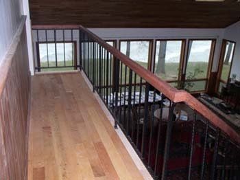 A wooden staircase with a metal railing leading to a living room.