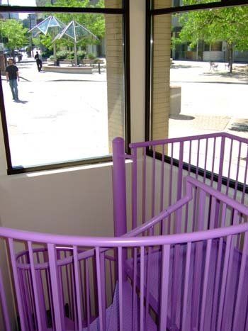 A purple spiral staircase with a window in the background