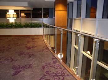 A hallway with a purple carpet and a glass railing