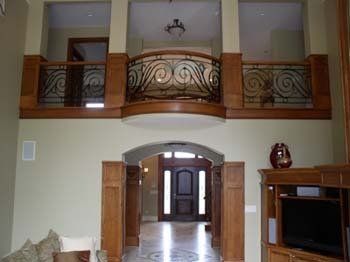 A living room with a balcony overlooking the entrance to a house.