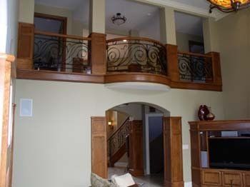 A living room with a balcony and stairs in a house.