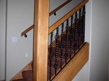 A wooden staircase with a wrought iron railing and handrails.