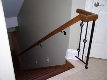 A staircase with a wooden handrail and a metal railing.