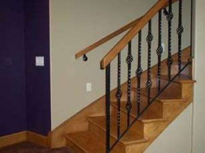A wooden staircase with a wrought iron railing in a room with purple walls.