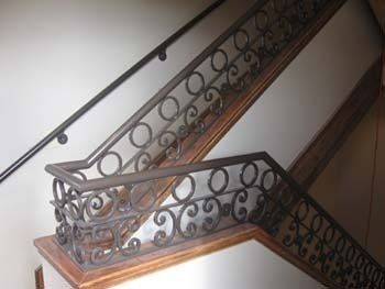 A close up of a wrought iron railing on a set of stairs.
