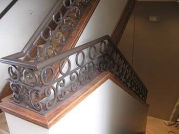 A wooden staircase with a wrought iron railing