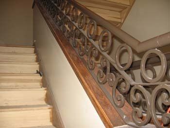 A close up of a staircase with a wrought iron railing.