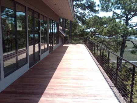A wooden deck with a metal railing and trees in the background